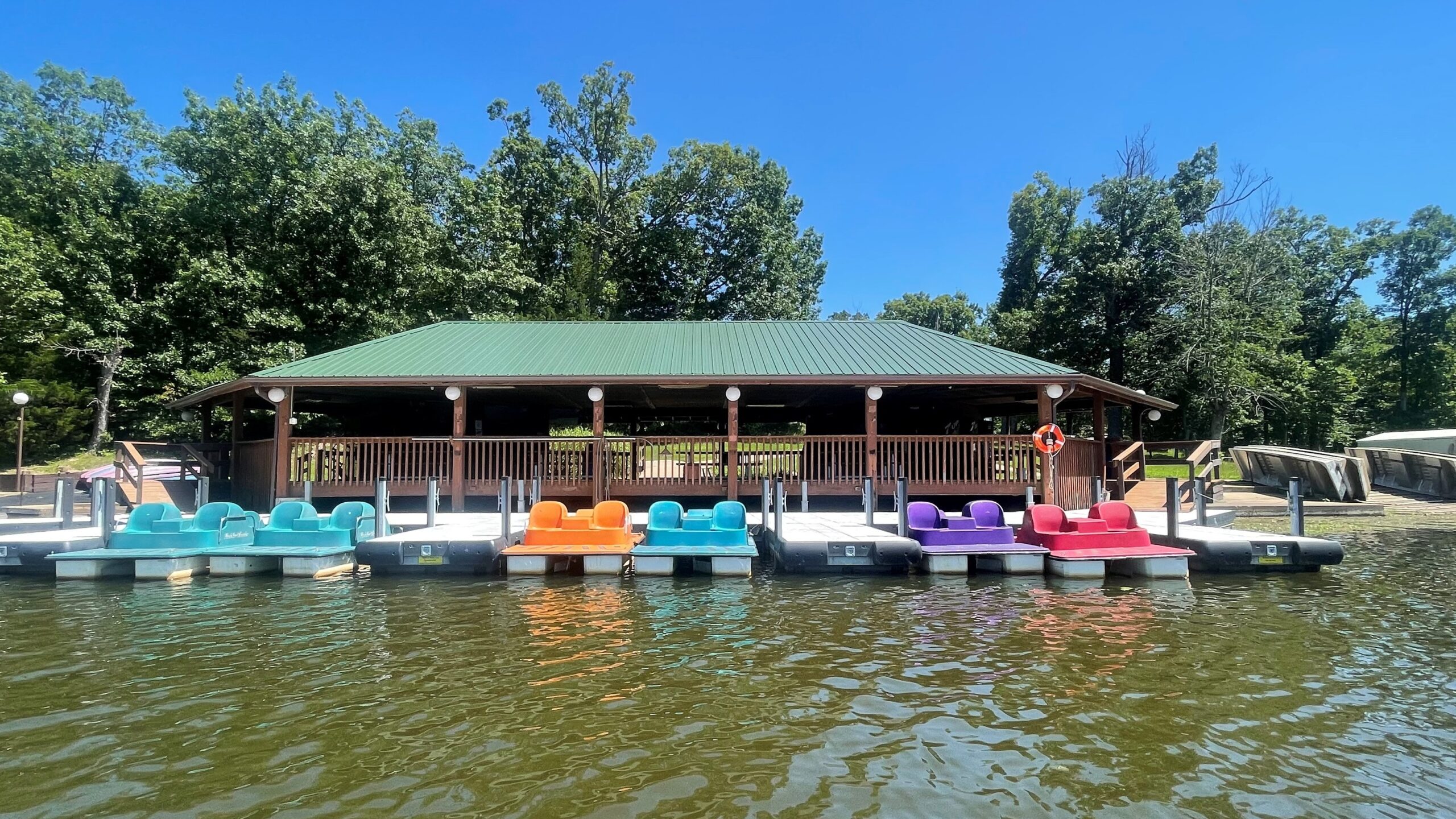 close picture of a boat house with a dock tied to it. paddle boats of various colors are stored here.