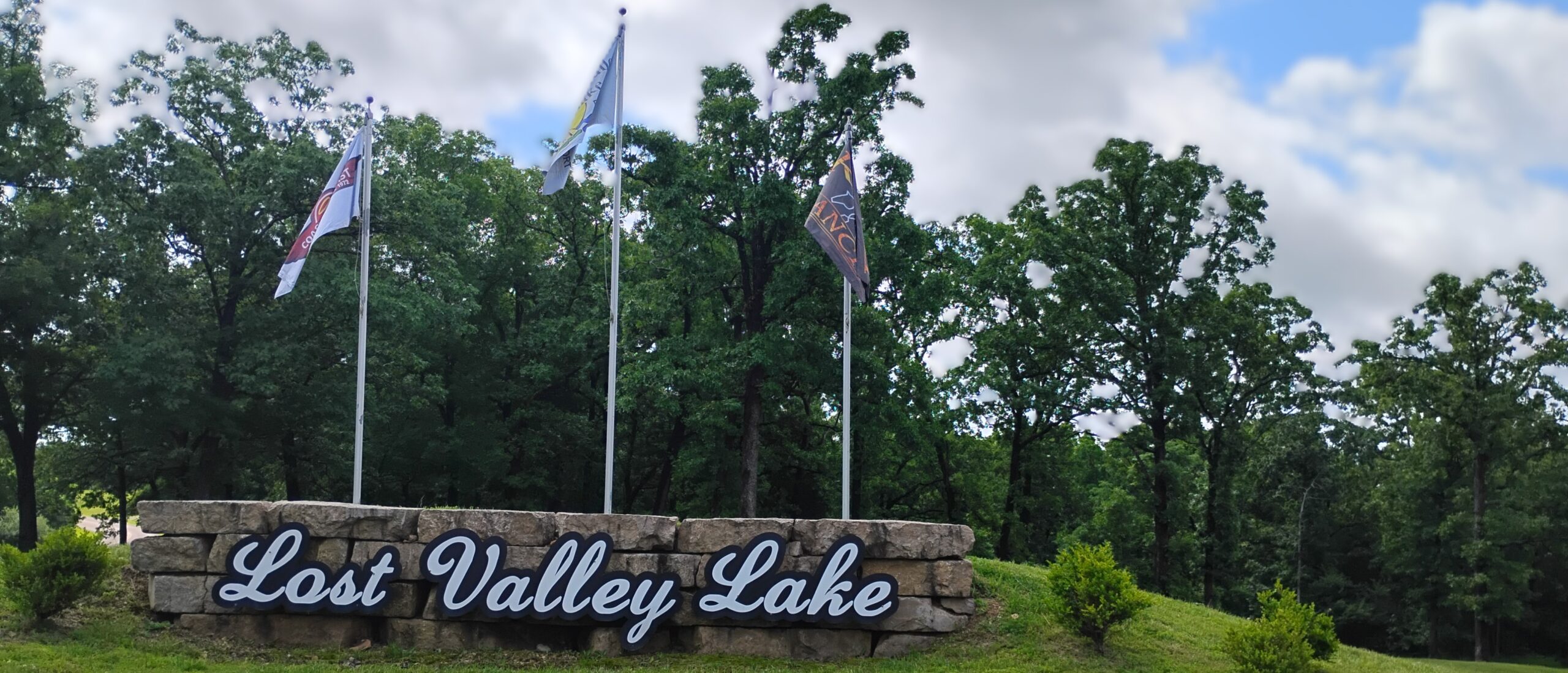 Entrance to lost valley lake with flag poles and a sign